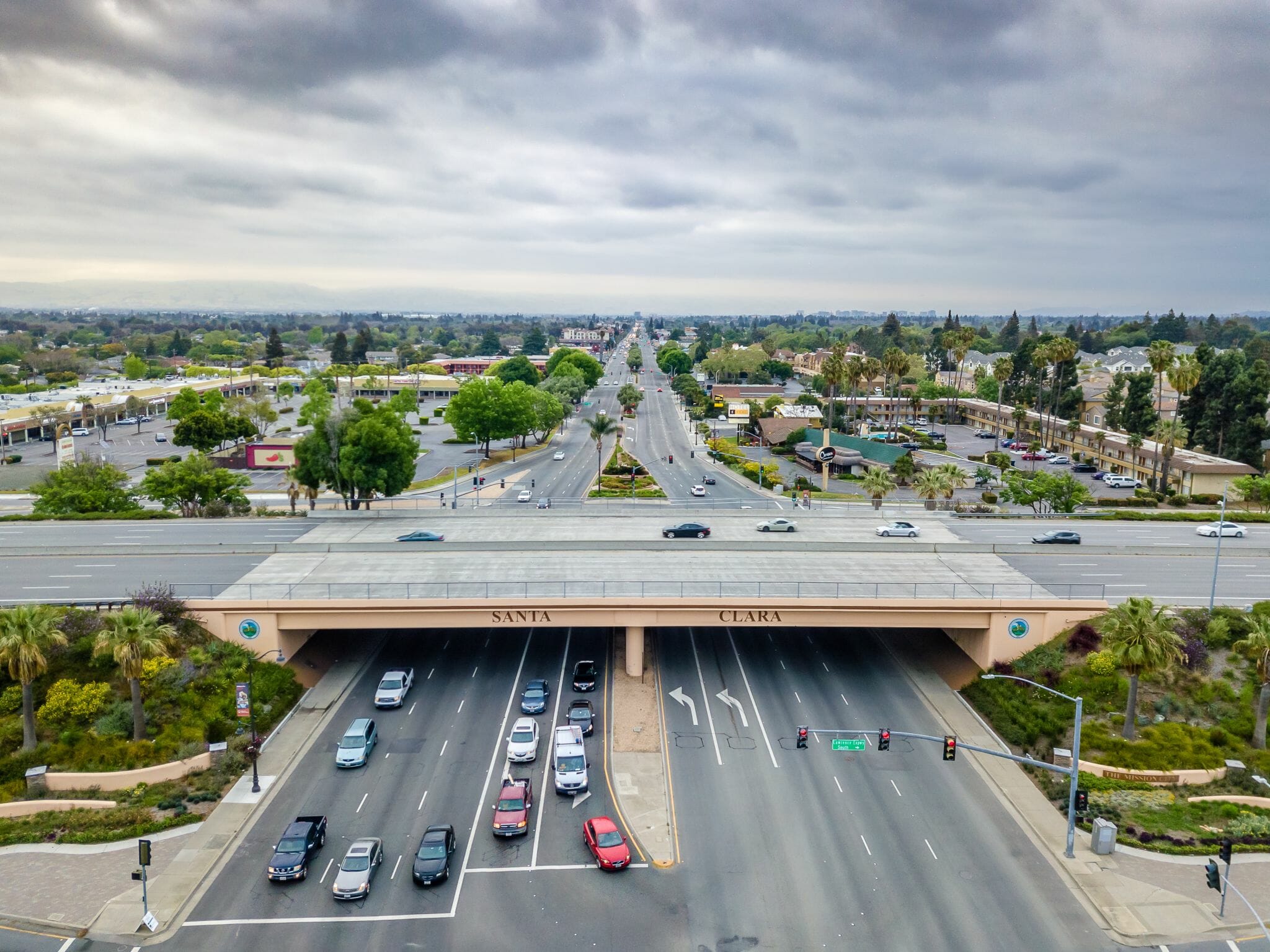 An expressway running under a bridge marked Santa Clara, with the city stretching to the horizon