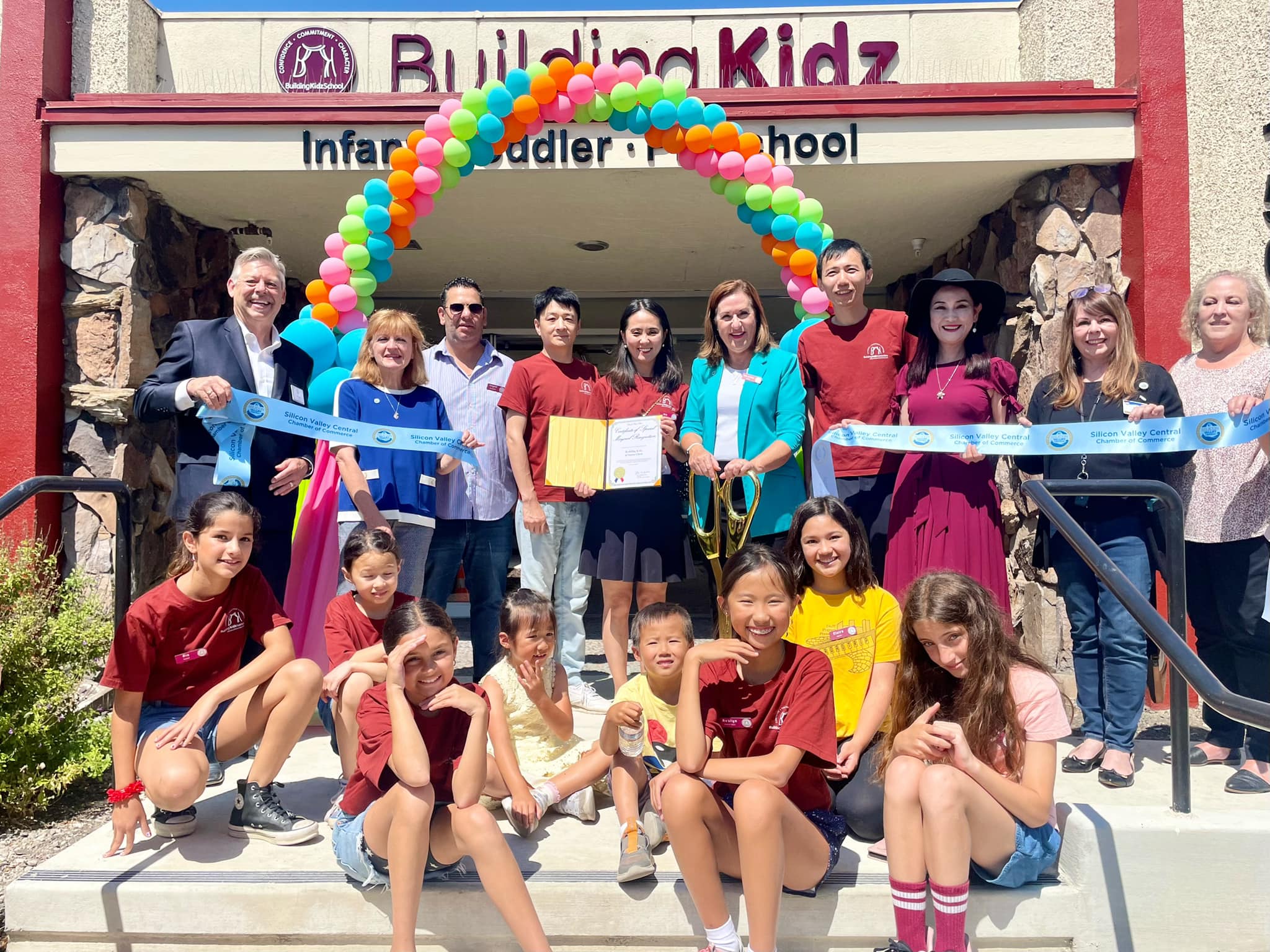 Ribbon cutting outside Building Kidz preschool with children in the front row