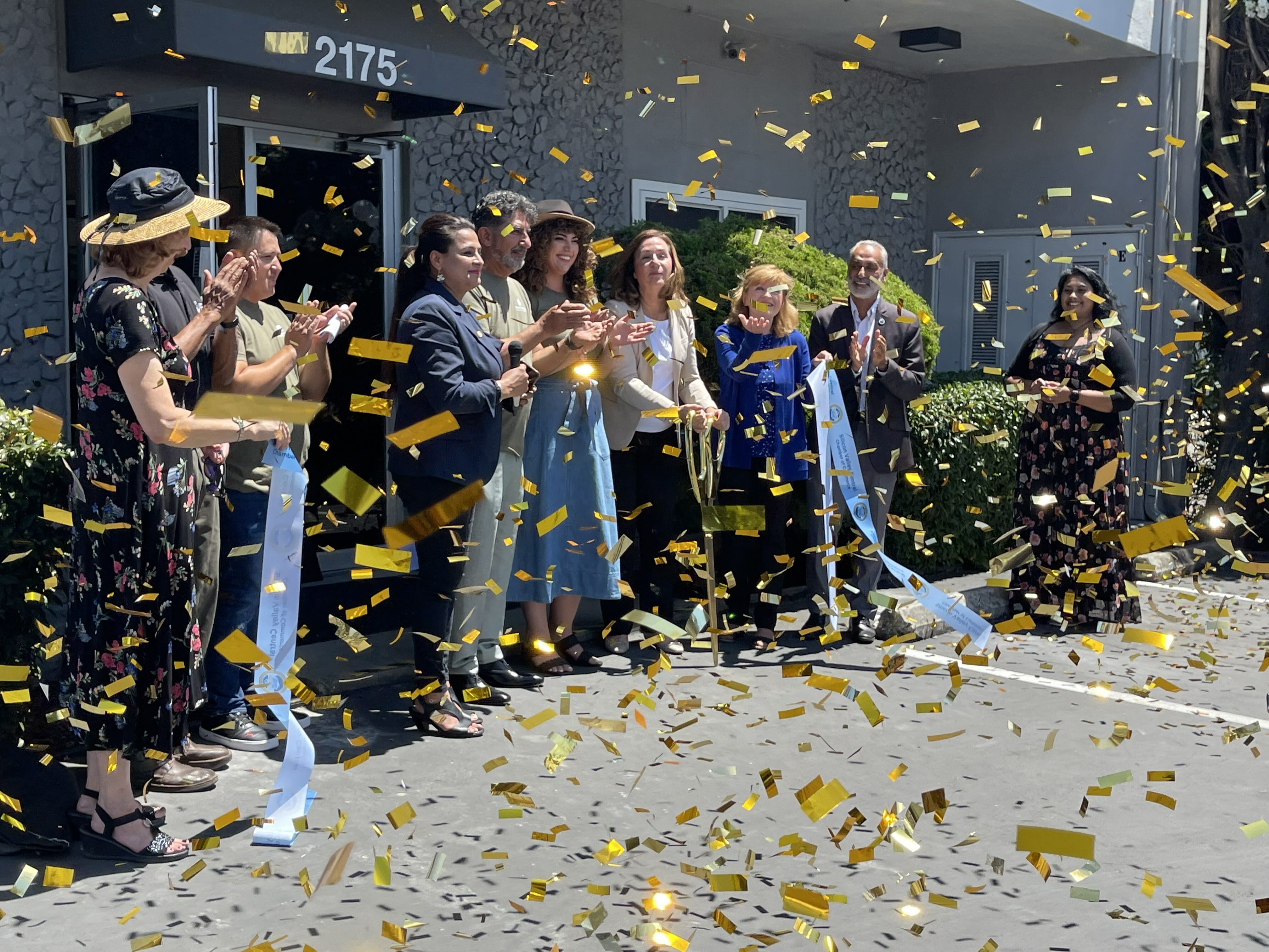 Gold confetti falling over the crowd as a Chamber ribbon is cut outside TriCore